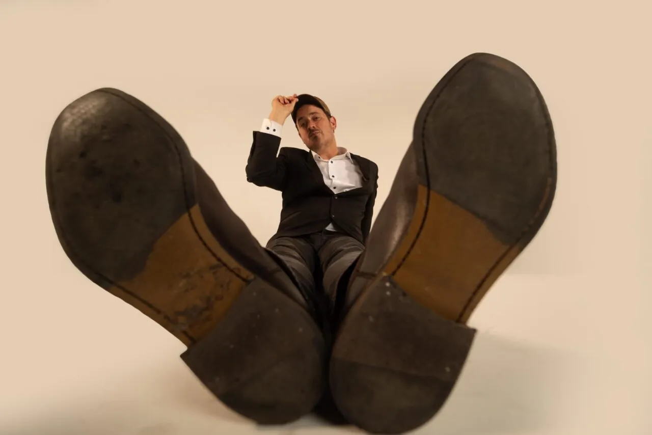 Author Josh Malerman seated in brown shoes