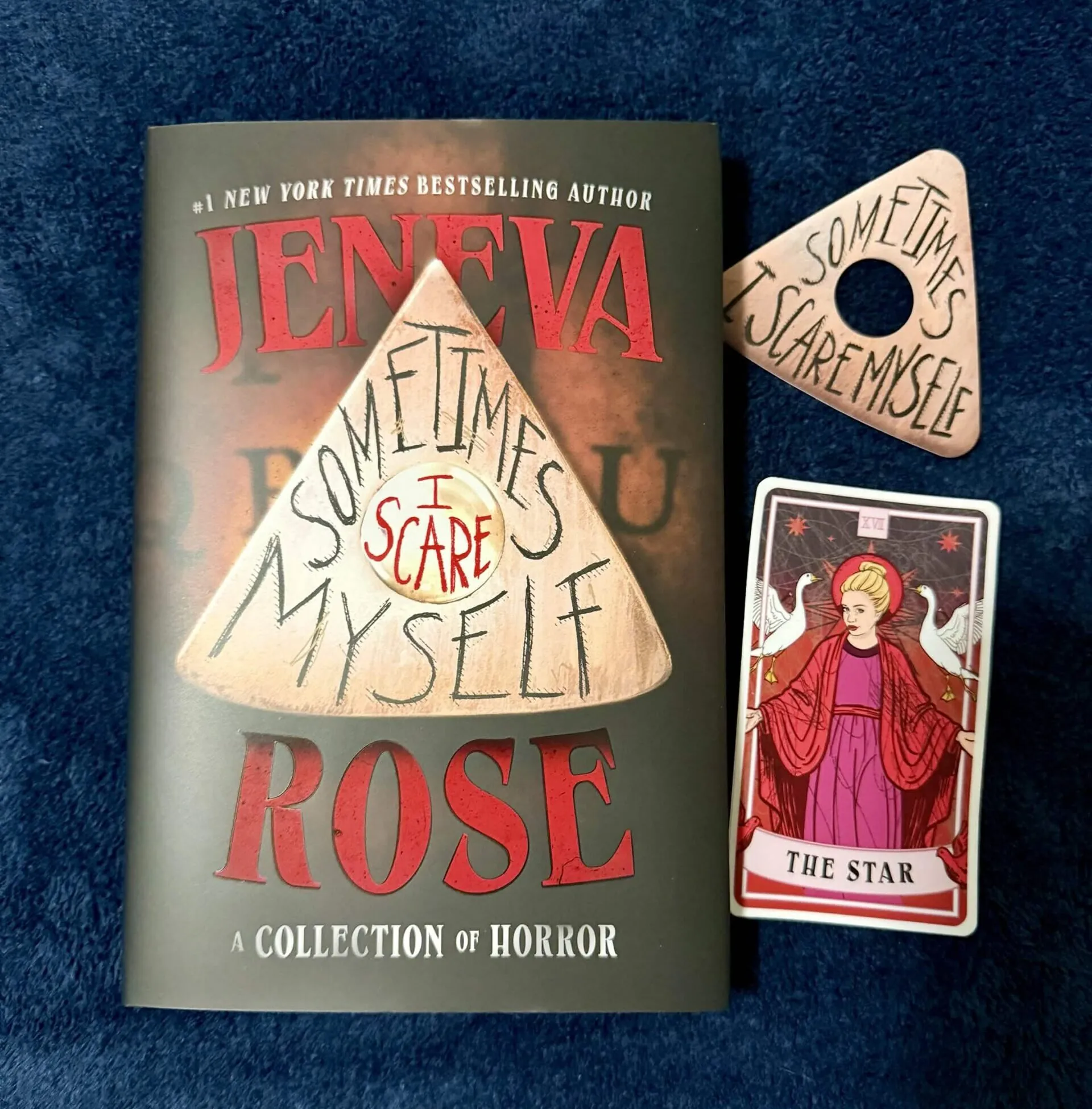 A hardcover copy of Jeneva Rose's SOMETIMES I SCARE MYSELF a planchette bookmark and the photographer's Tarot Card.