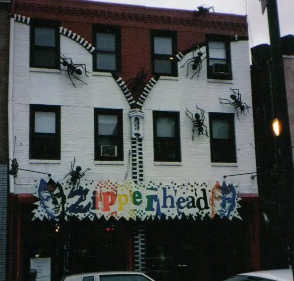 Iconic, defunct punk clothing store on South Street in Philadelphia. Faturing gargantuan 3D ants climbing down a zipper faceted to the building above text that reads ZIPPERHEAD.