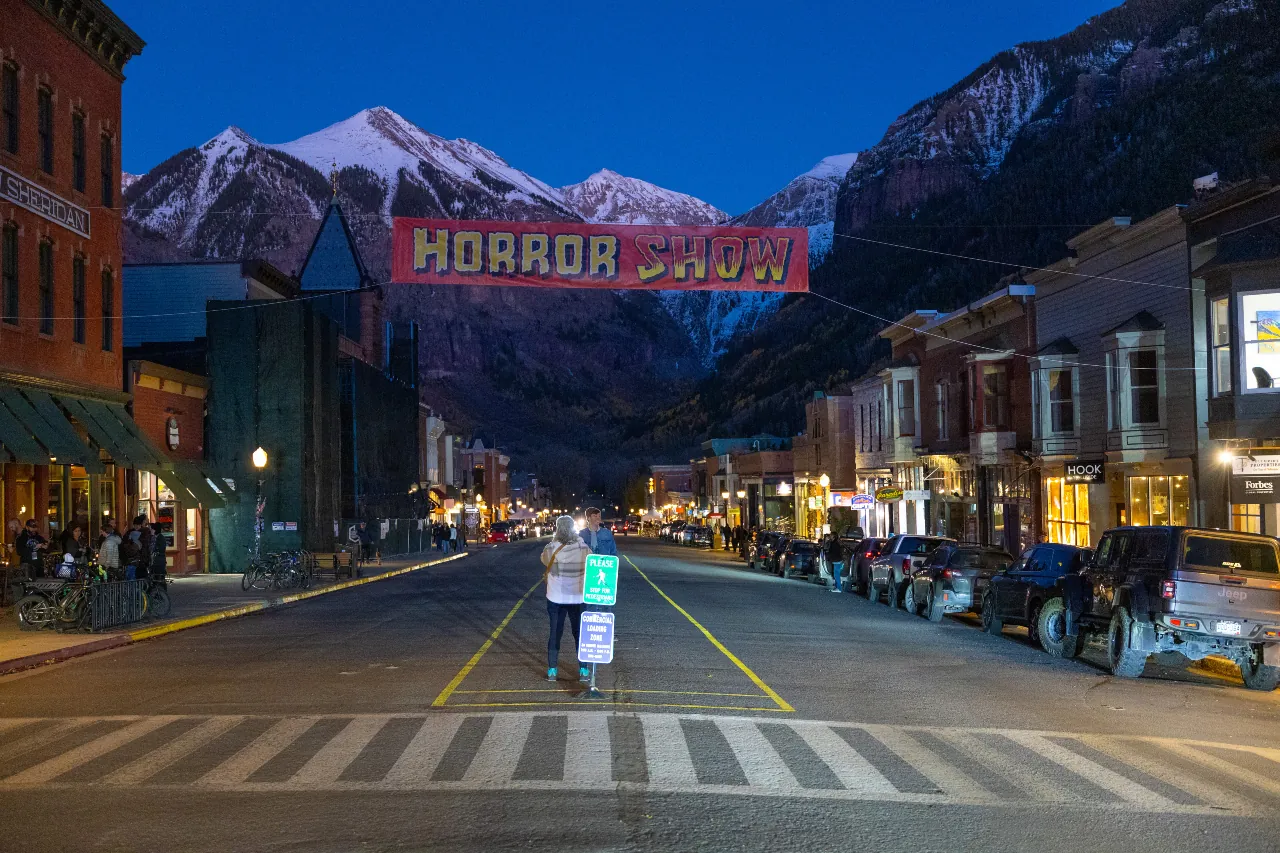 Banner reading "Horror Show" stretched out across Main Street in Telluride at dusk, mountains in the background.