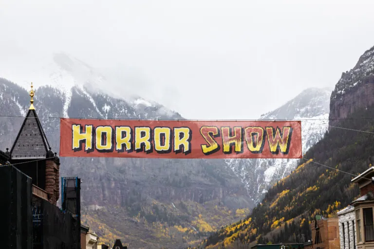 Banner reading "Horror Show" stretched out across Main Street in Telluride, mountains in the background.